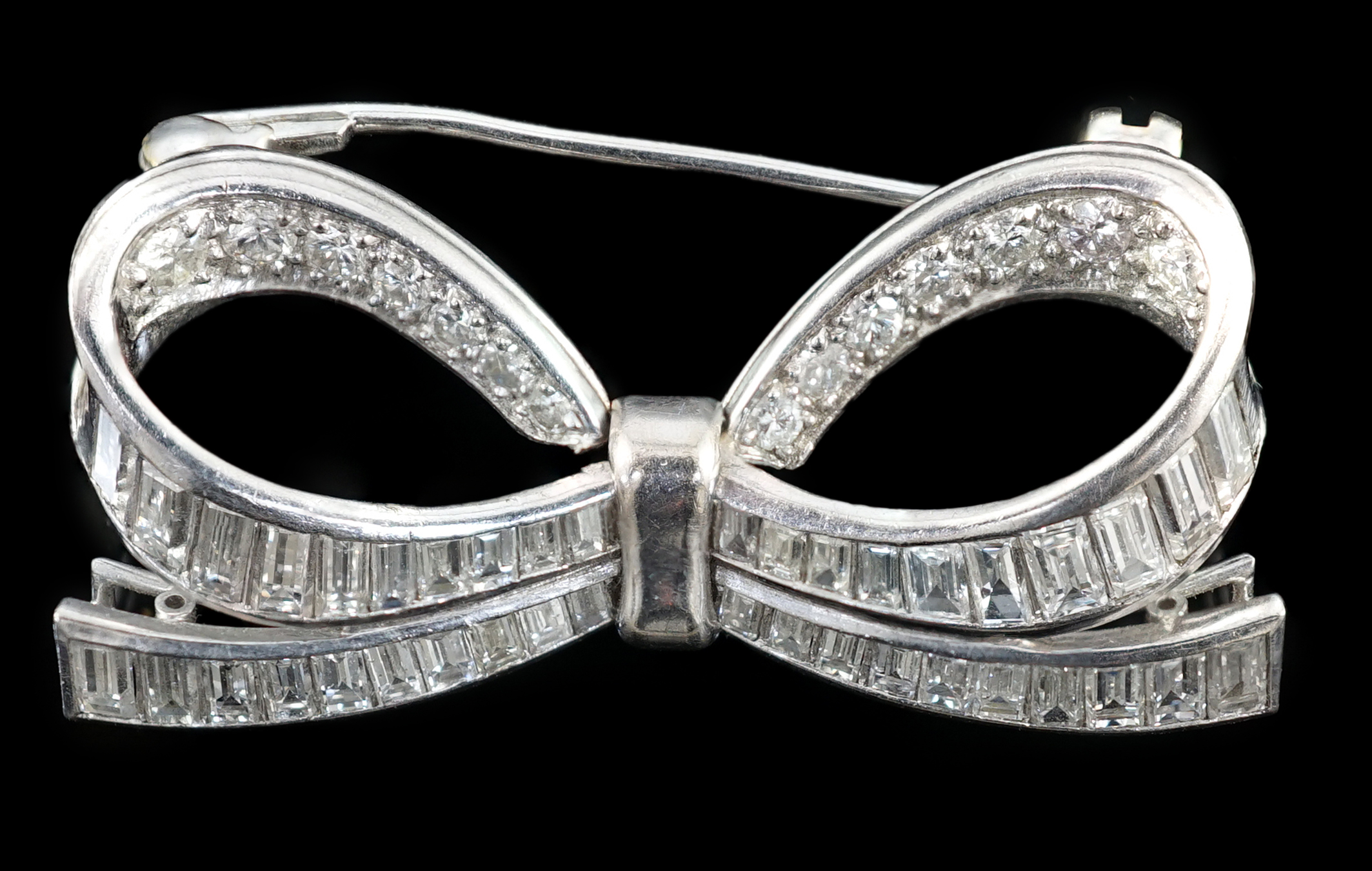 A modern white gold and round and baguette cut diamond cluster set ribbon bow brooch